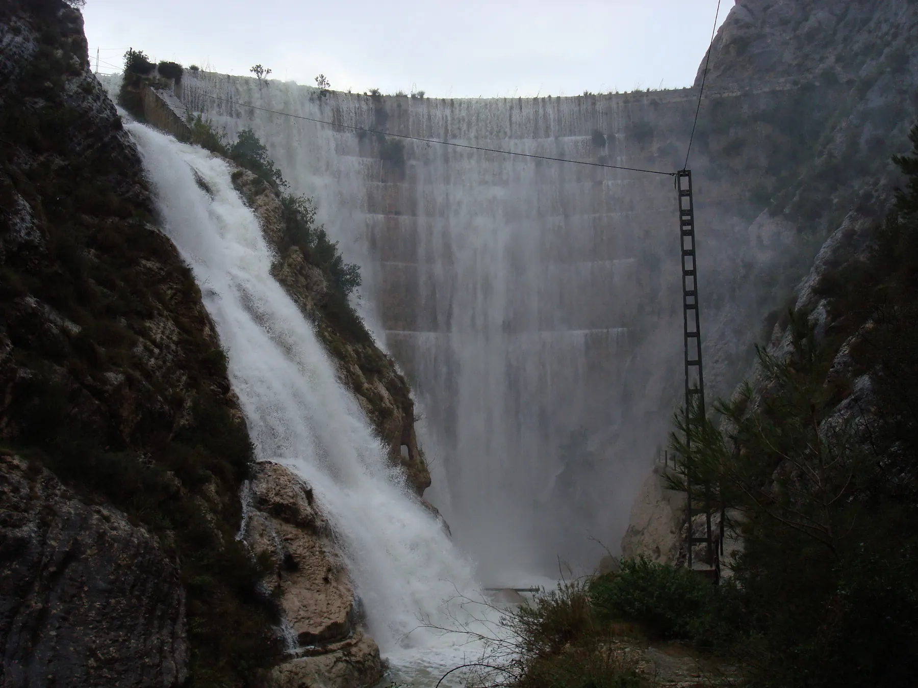 Presa de Tibi, del siglo XVI, con el agua desbordando por el aliviadero entre paredes de roca