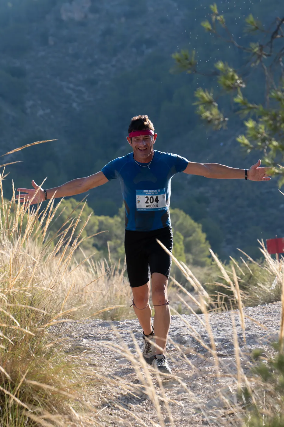 Corredor con los brazos abiertos en una senda de montaña de Tibi durante el trail de 2025
